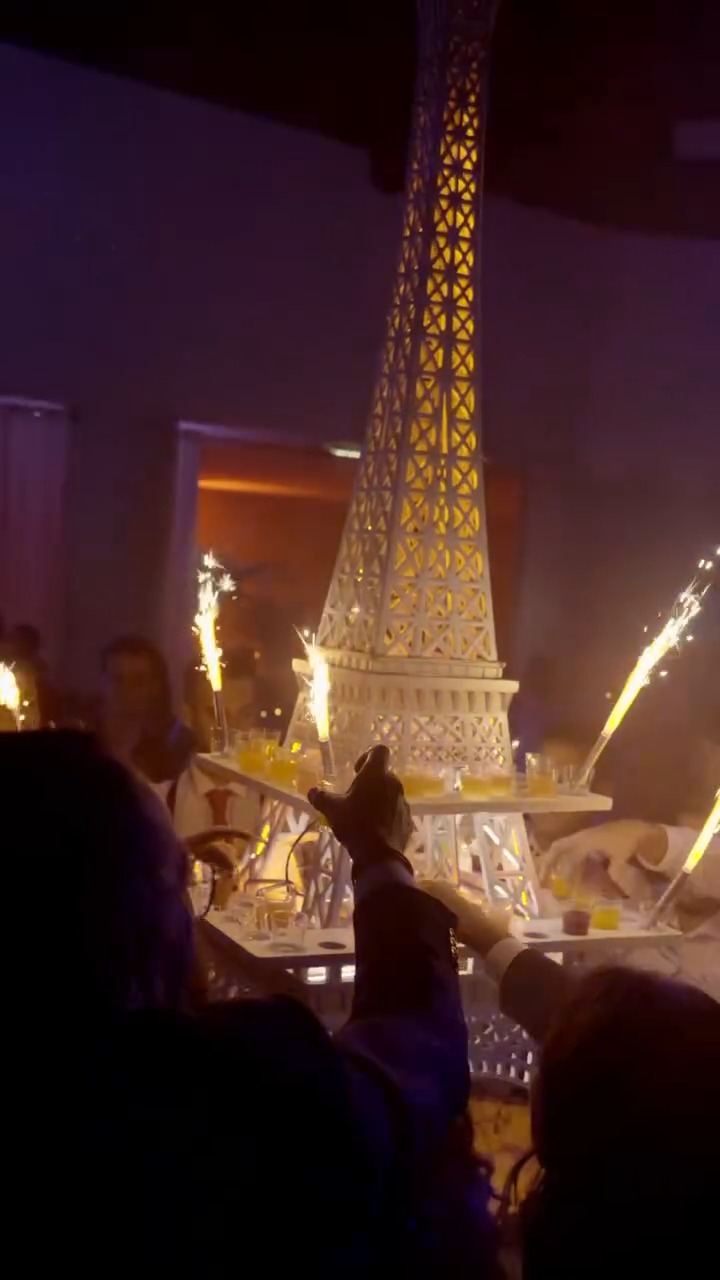 La Tour Eiffel de shots entourée de fontaines lumineuses, un invité vient prendre son verre